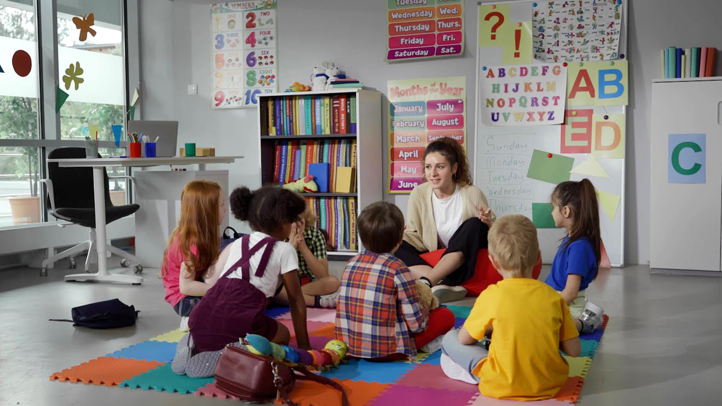 a teacher and small children sitting on the floor of a childcare classroom