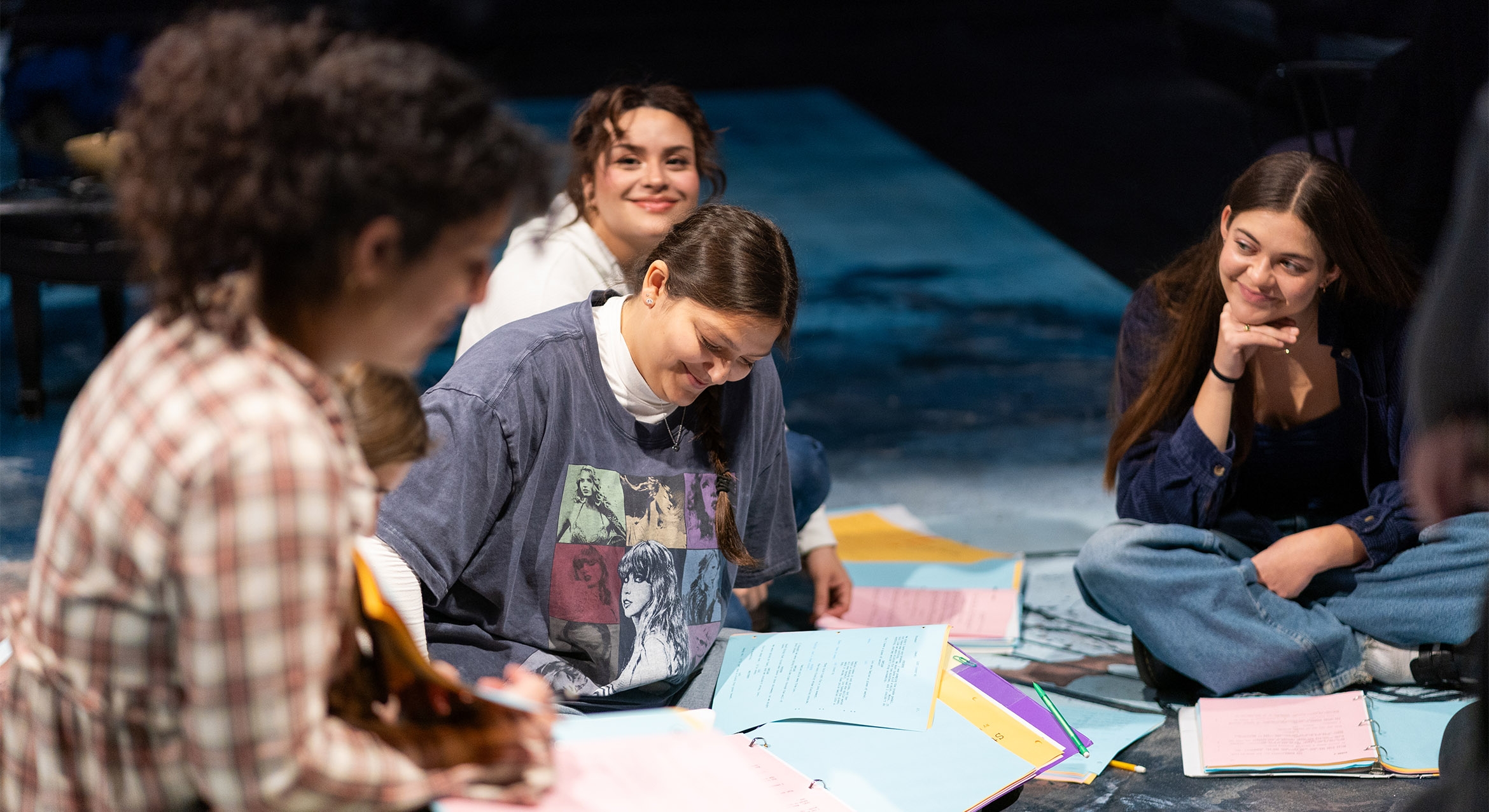 Four women sitting on a stage surrounded by pieces of paper