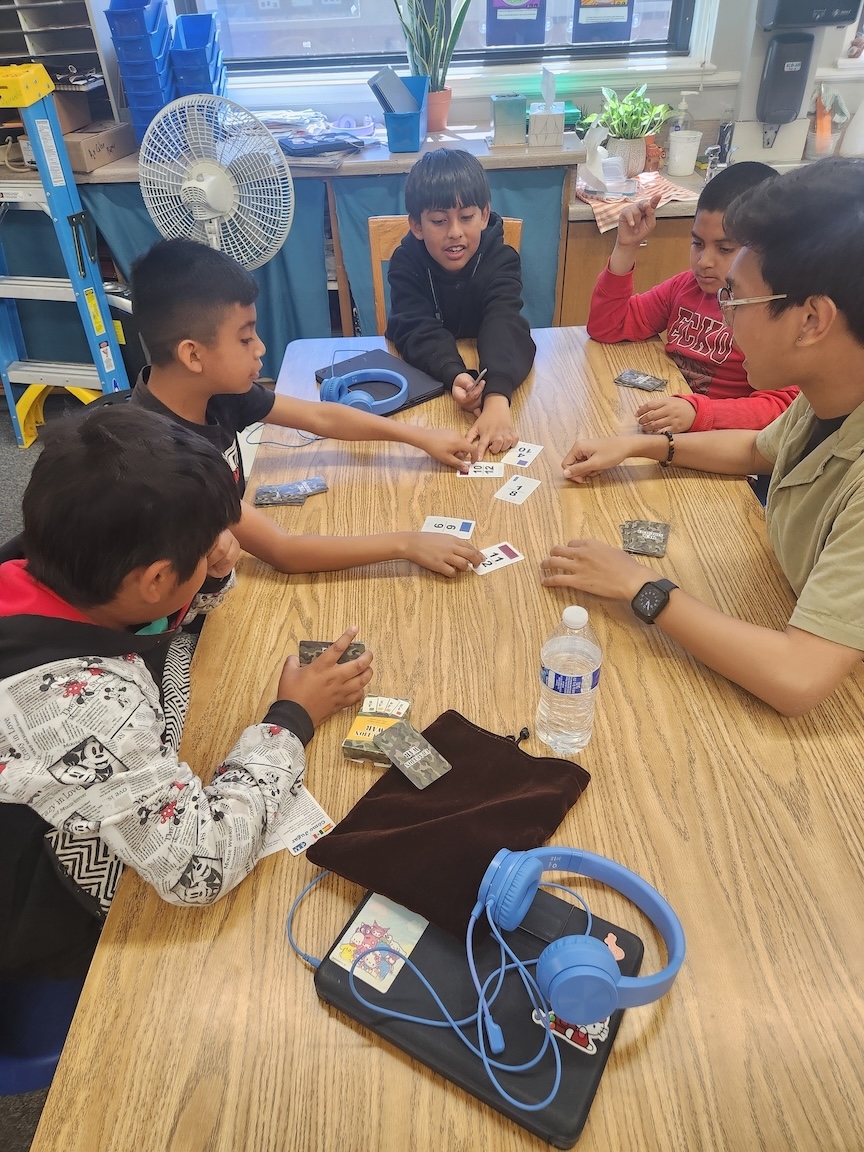 Elementary age students sitting around a table playing a game