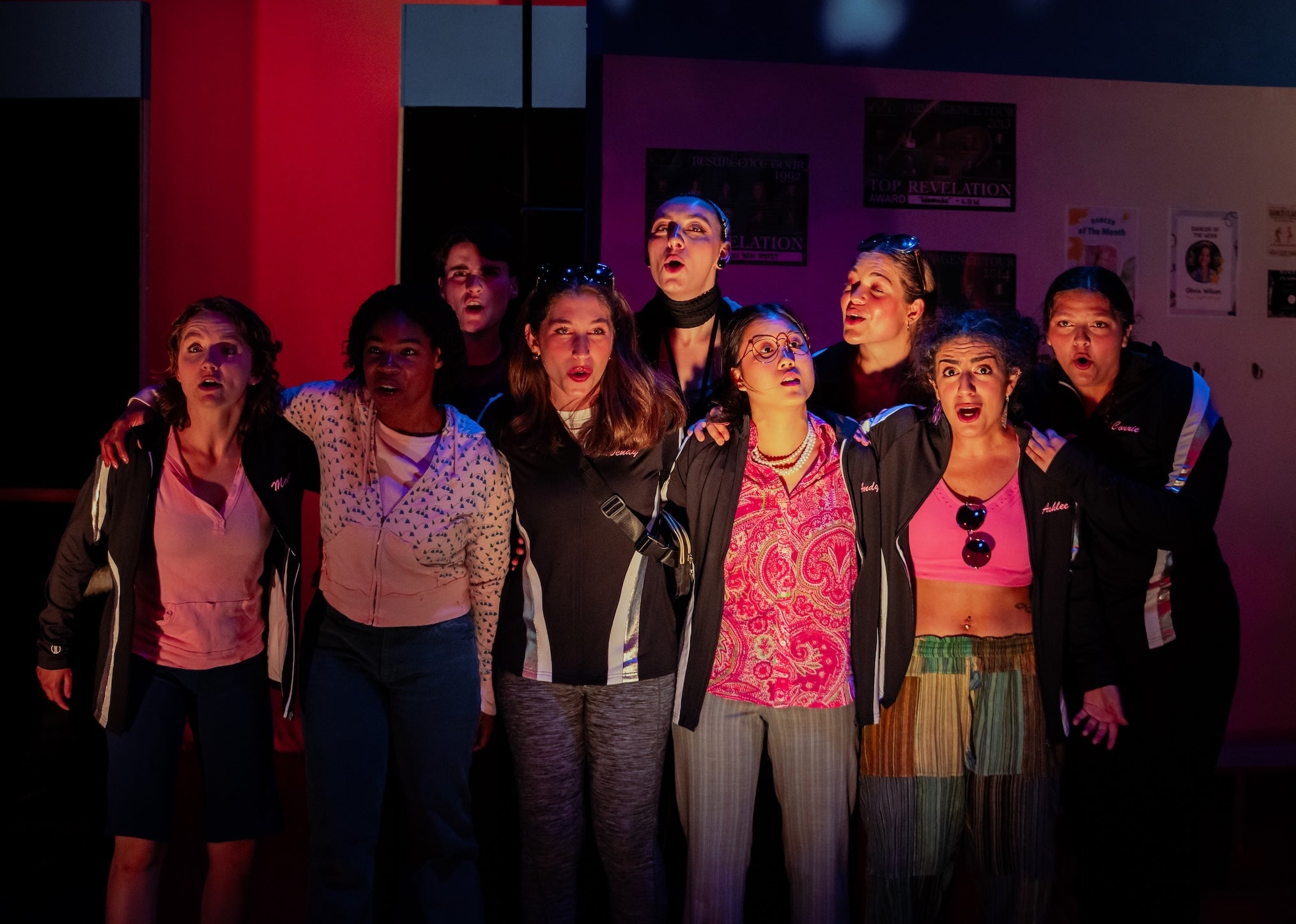 A group of women darkly lit with mouths open in song