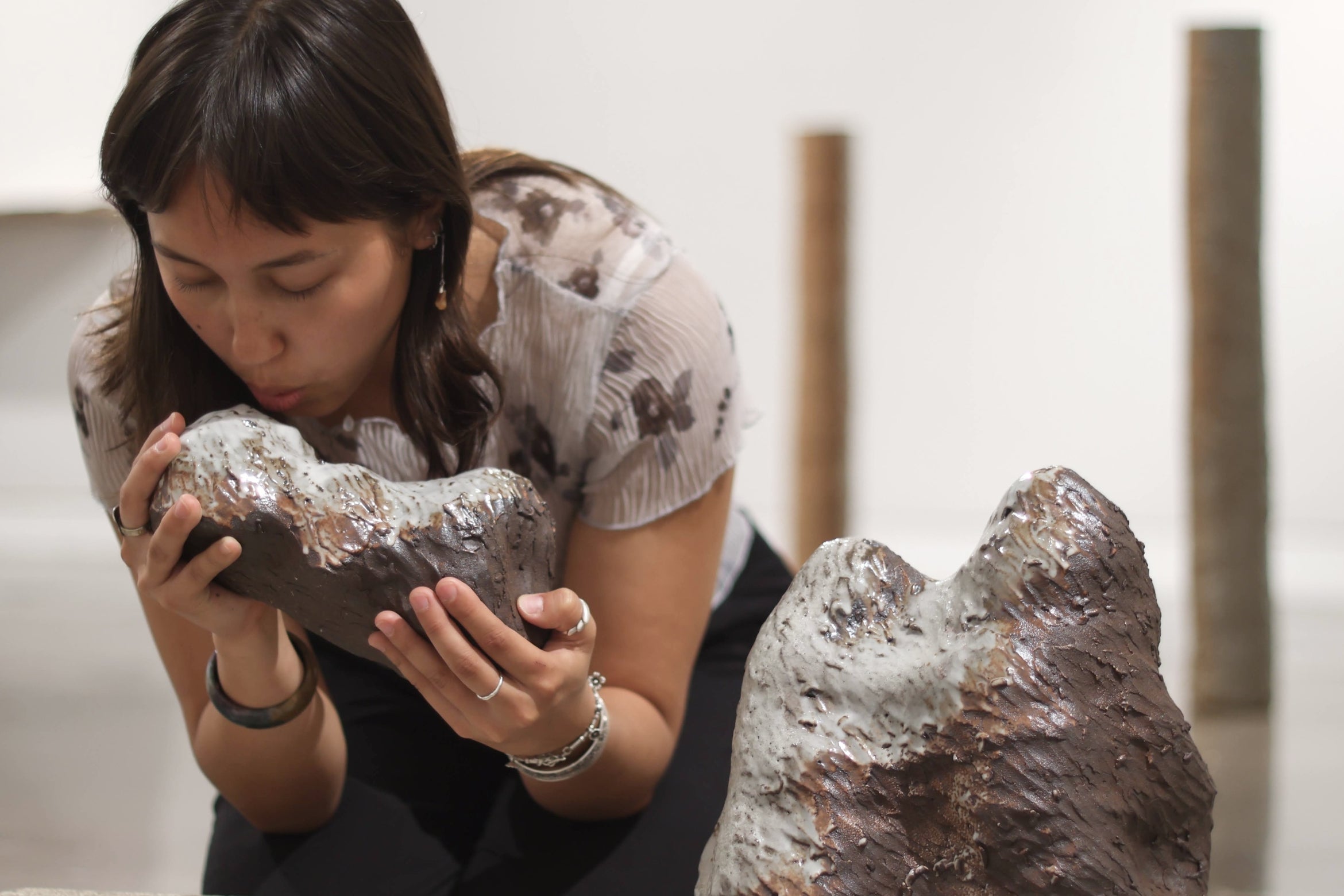 Woman kneels down with ceramic vessel in museum space