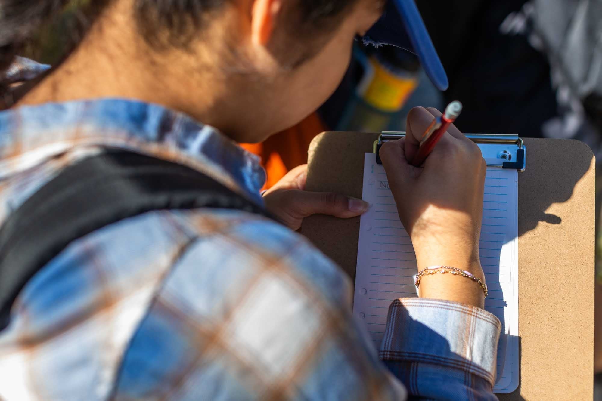 student taking notes on a cliipboard