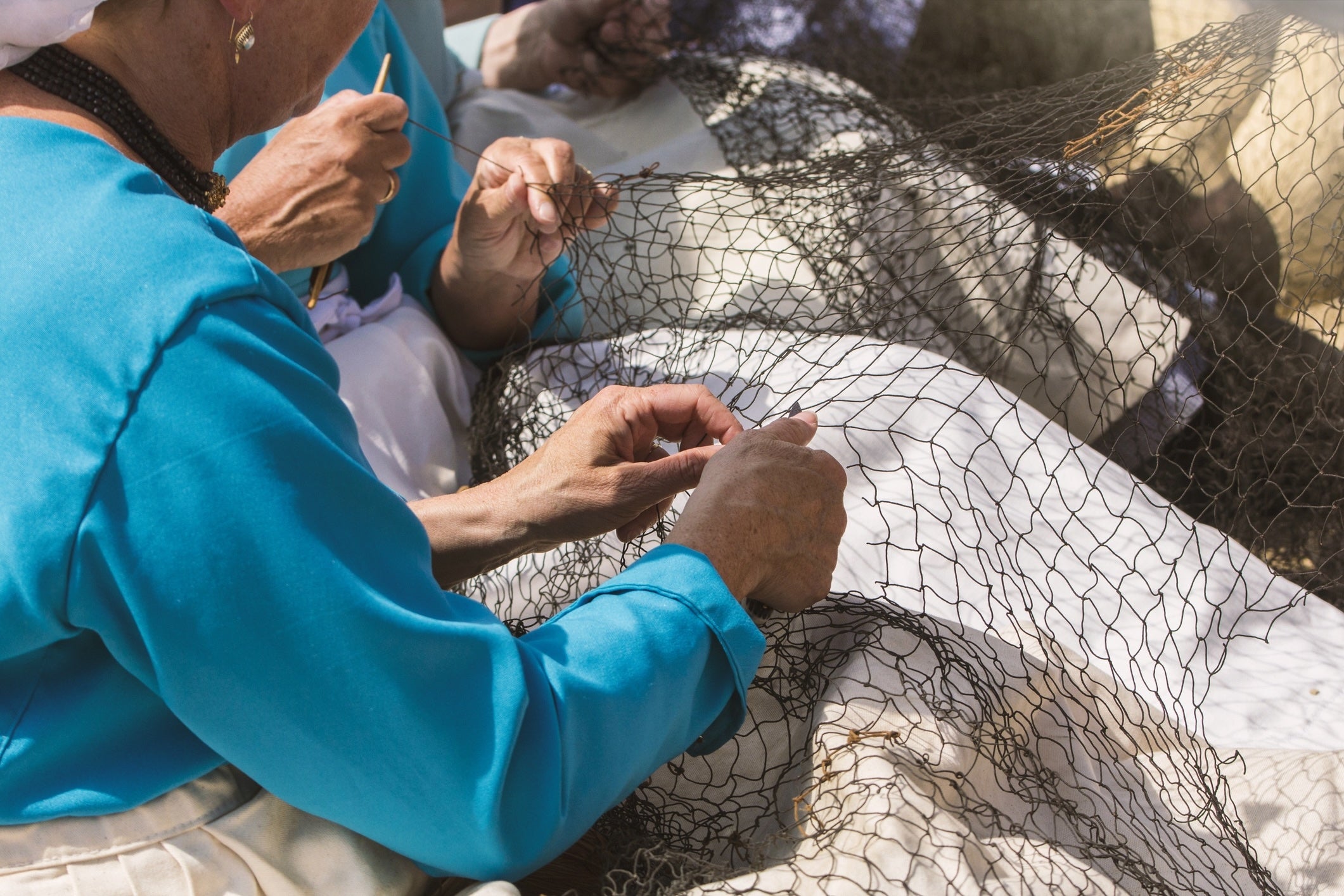 women weaving and mending fishing nets