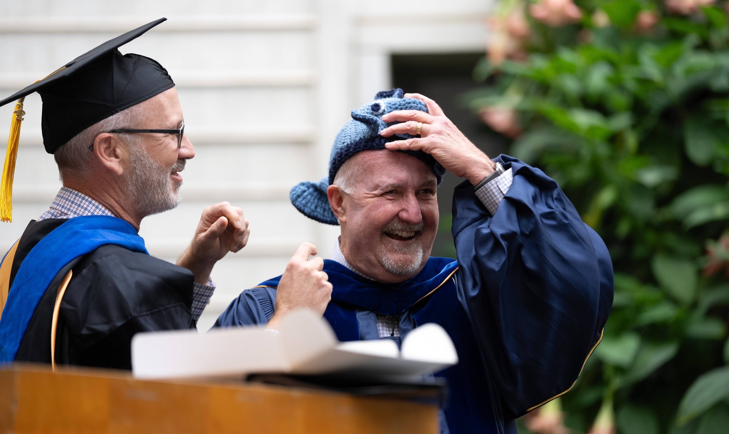 Professor Ben Halpern hoods Dean Steve Gaines with a blue fish beanie.