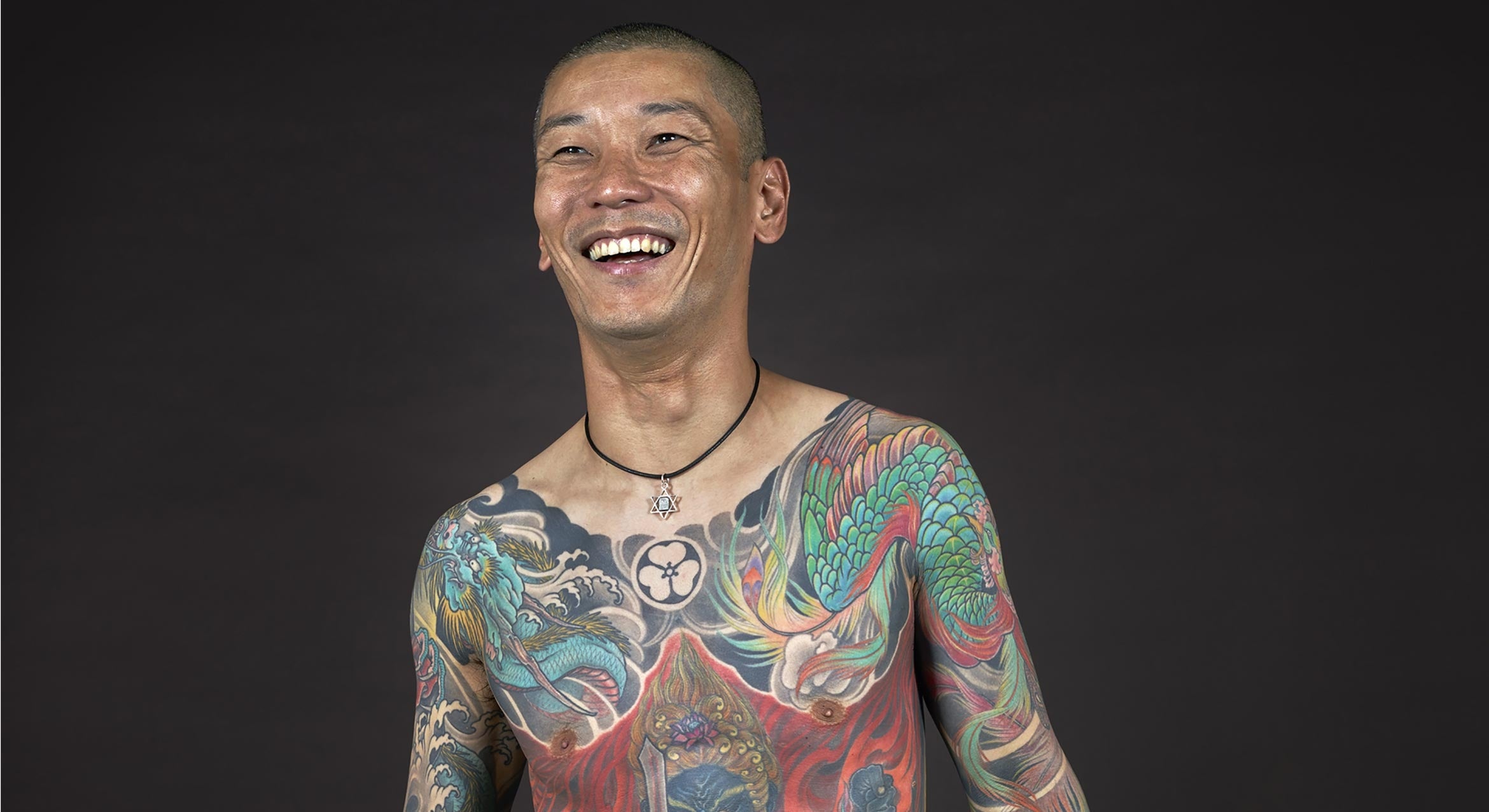 man smiling with full chest Japanese tattoo