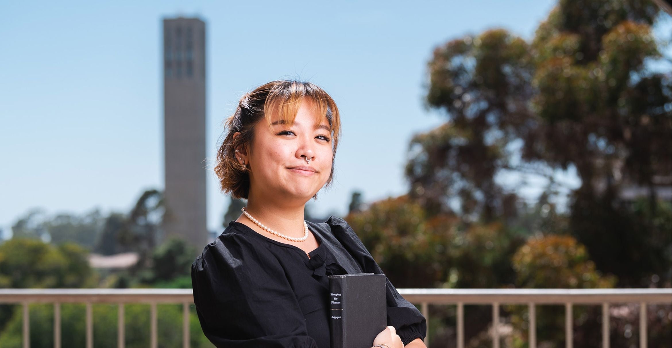 color photograph of a student outside holding a book