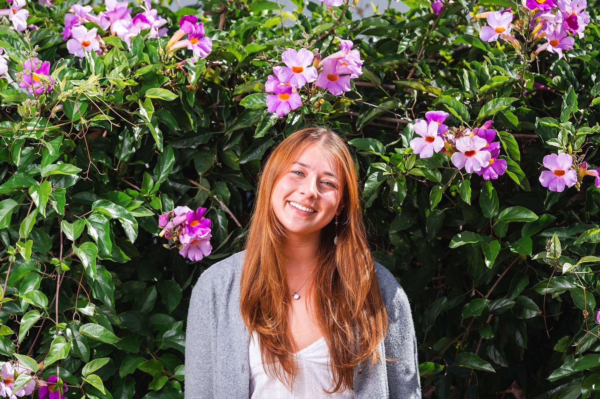 color photograph of a woman outside standing in front of flowers