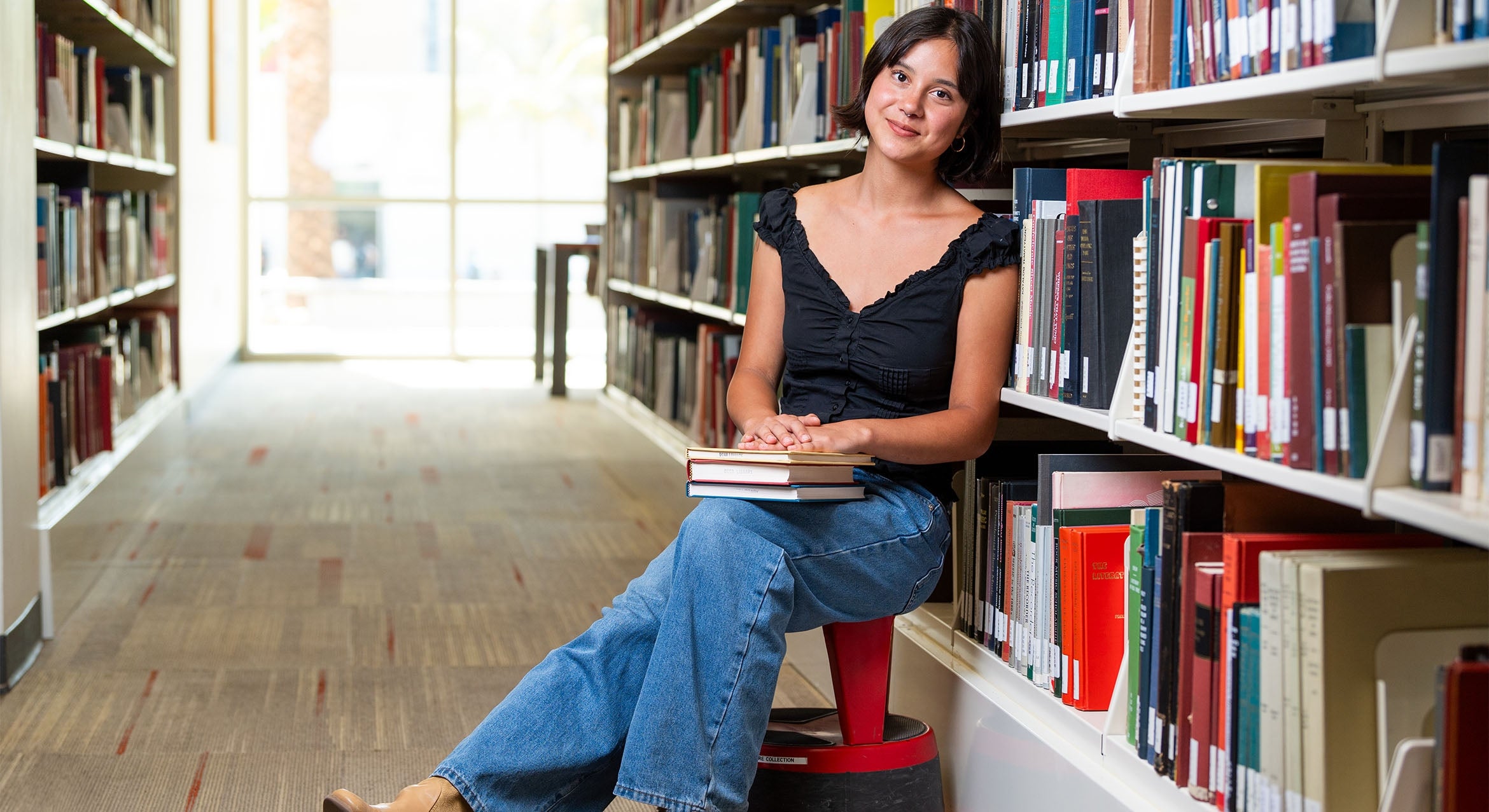 color photograph of a student sitting among the stacks at the library