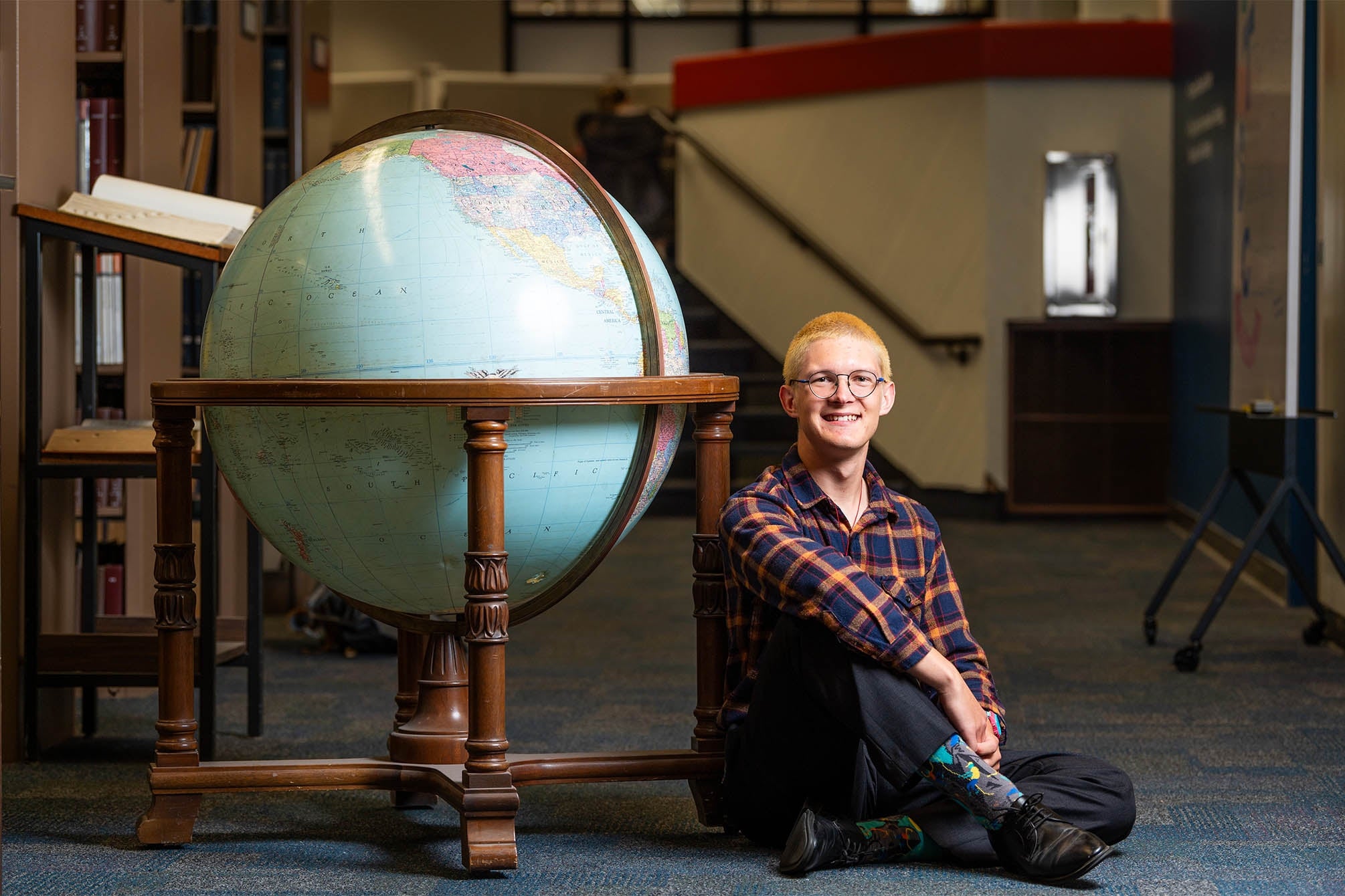 color photograph of a student sitting next to a large globe
