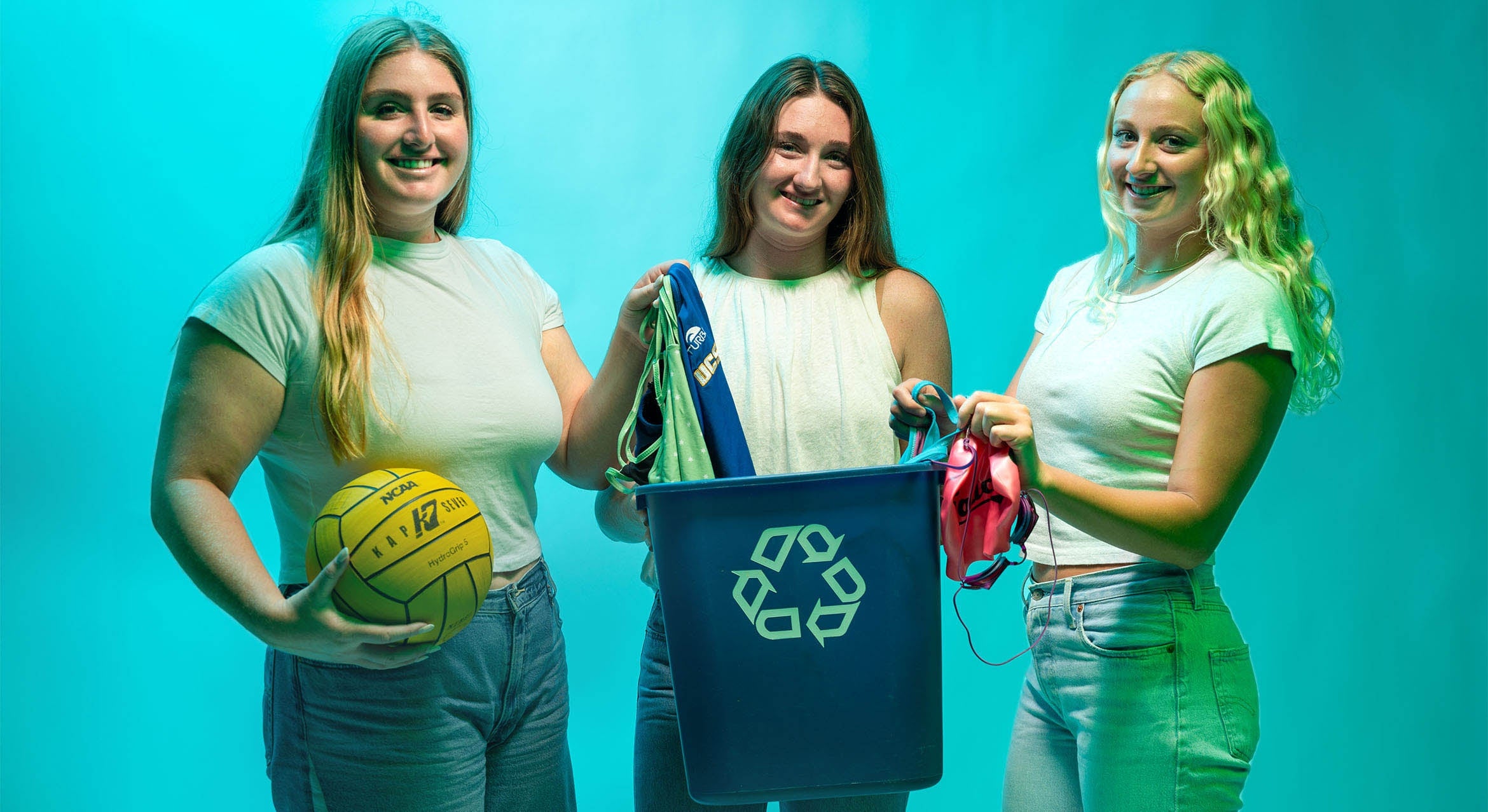 Three UCSB student athletes hold a recycling can