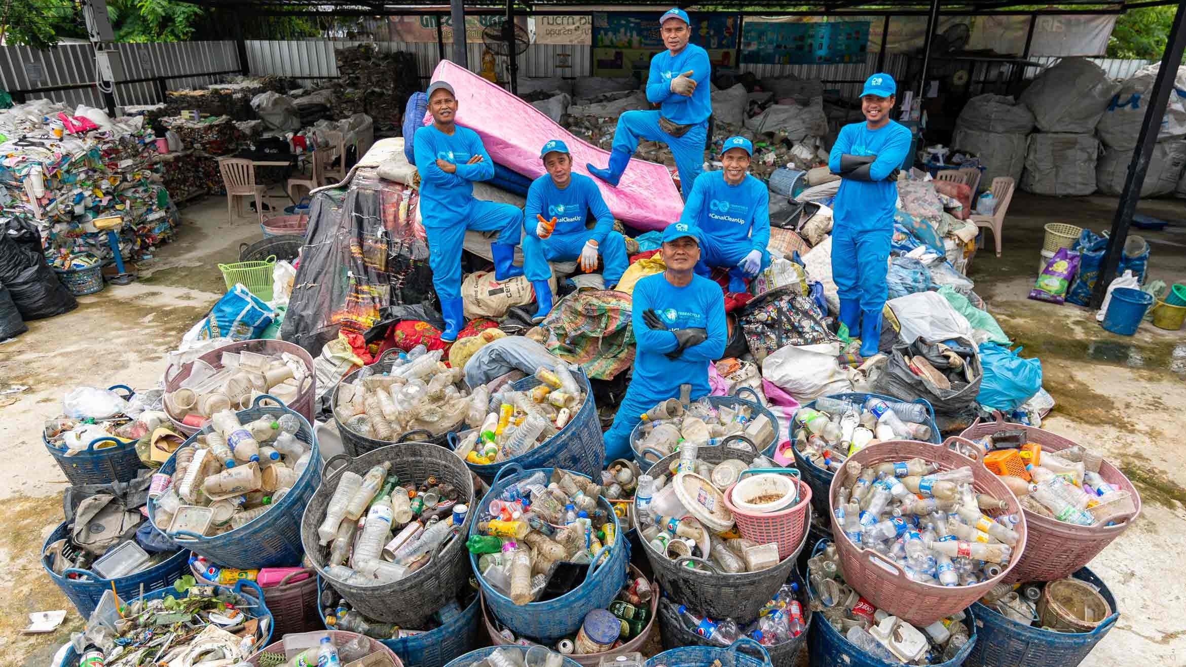 workers stand on top of barrels of plastic
