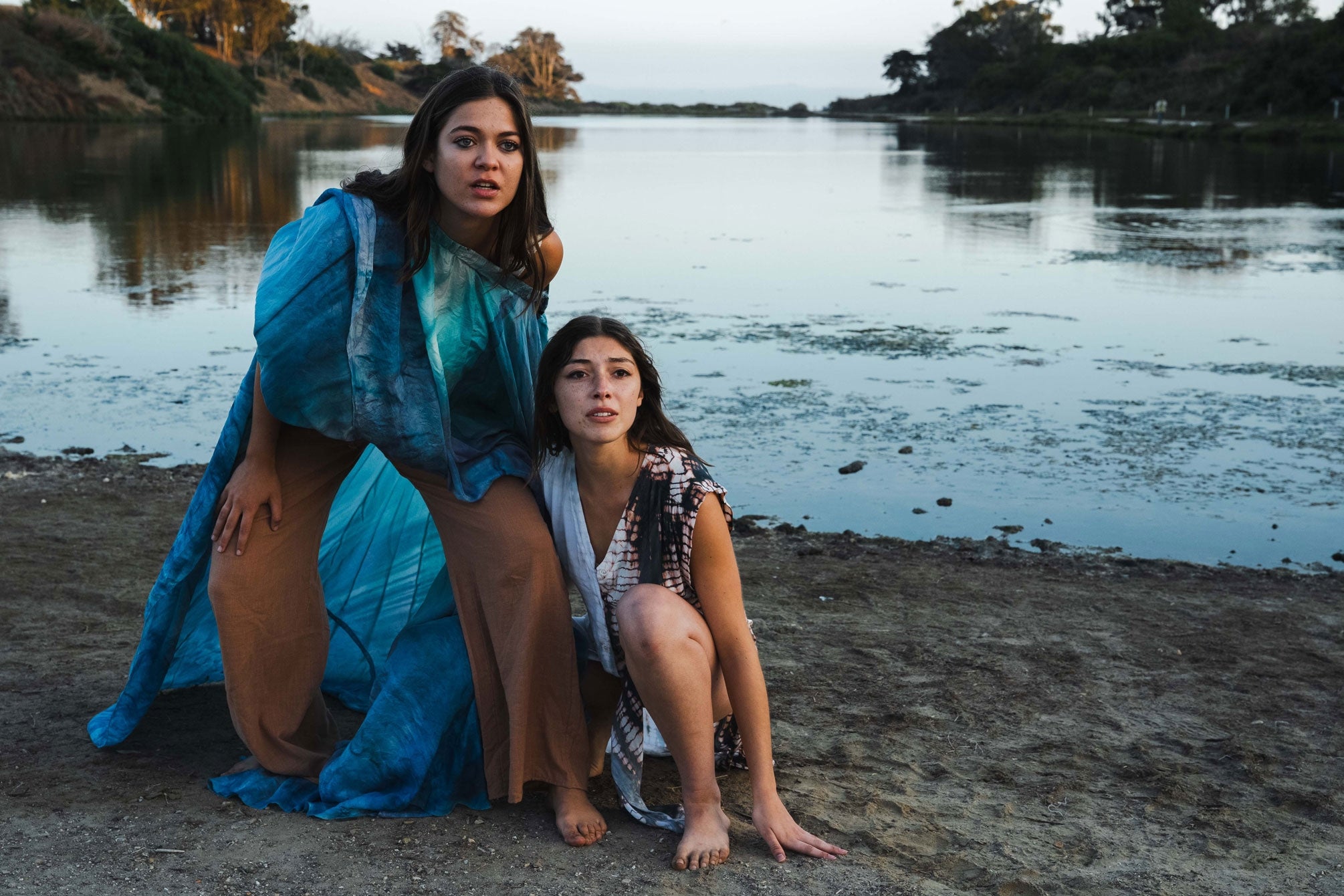 two actors in whimsical blue costumes on beach at sunset