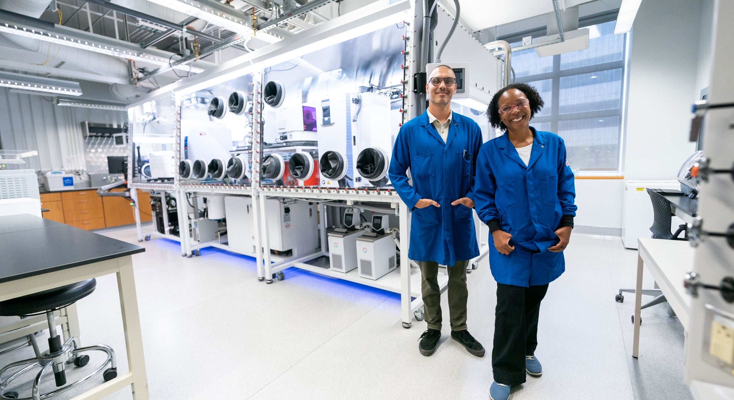 a Black woman and white man in blue lab coats in a lab