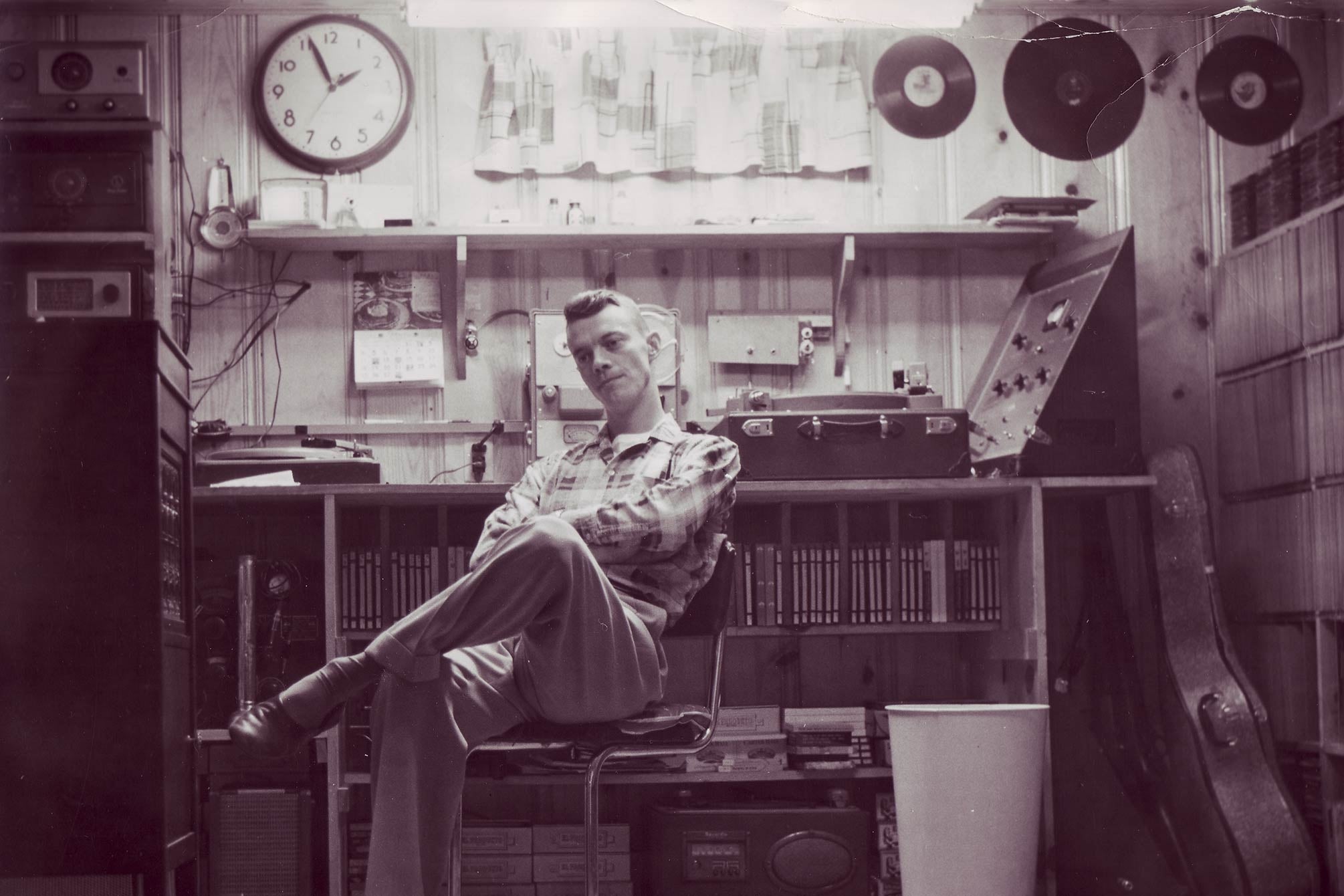 black and white photograph of joe bussard sitting in his basement radio station