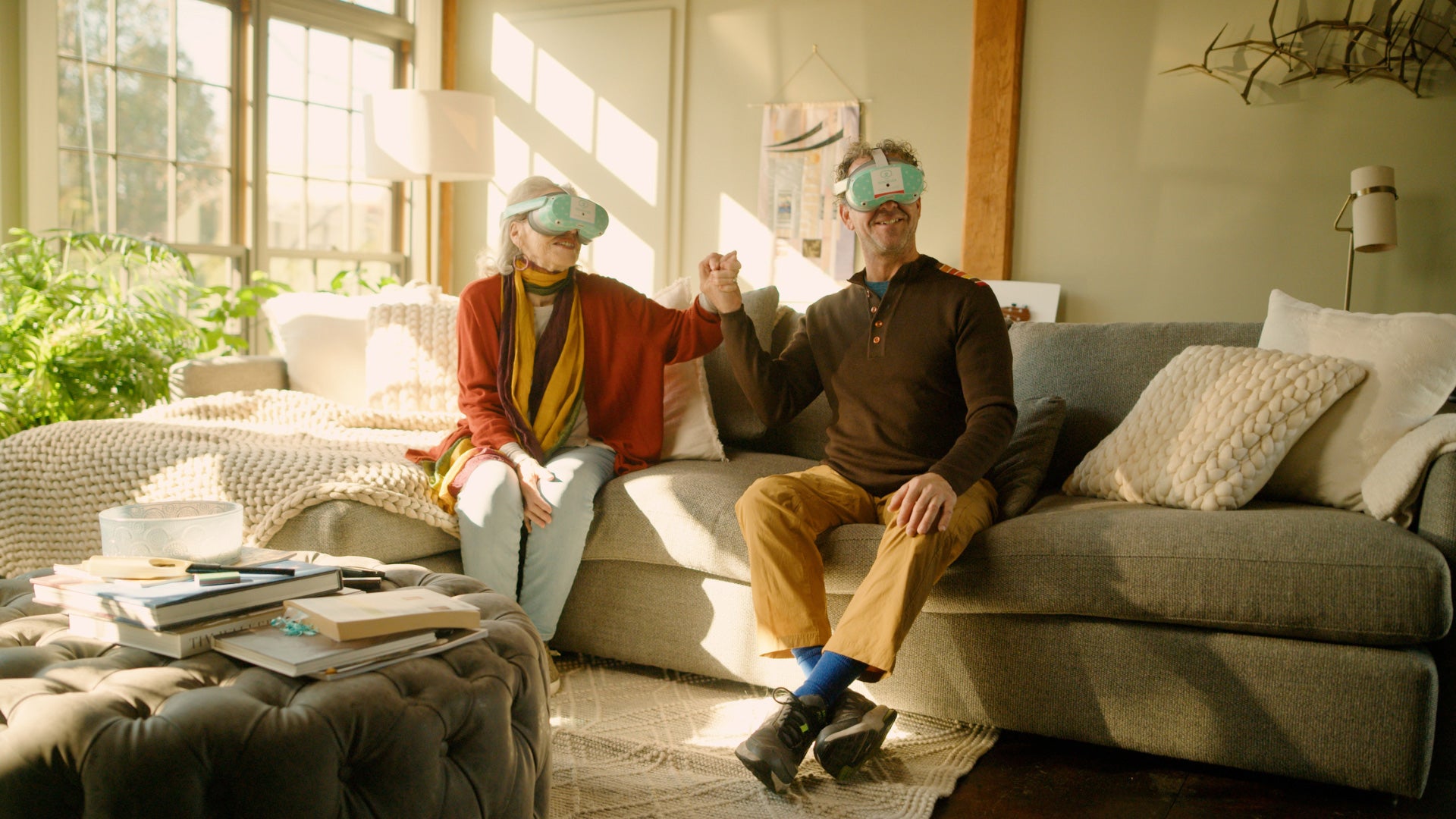 two older white people on couch with virtual reality headsets