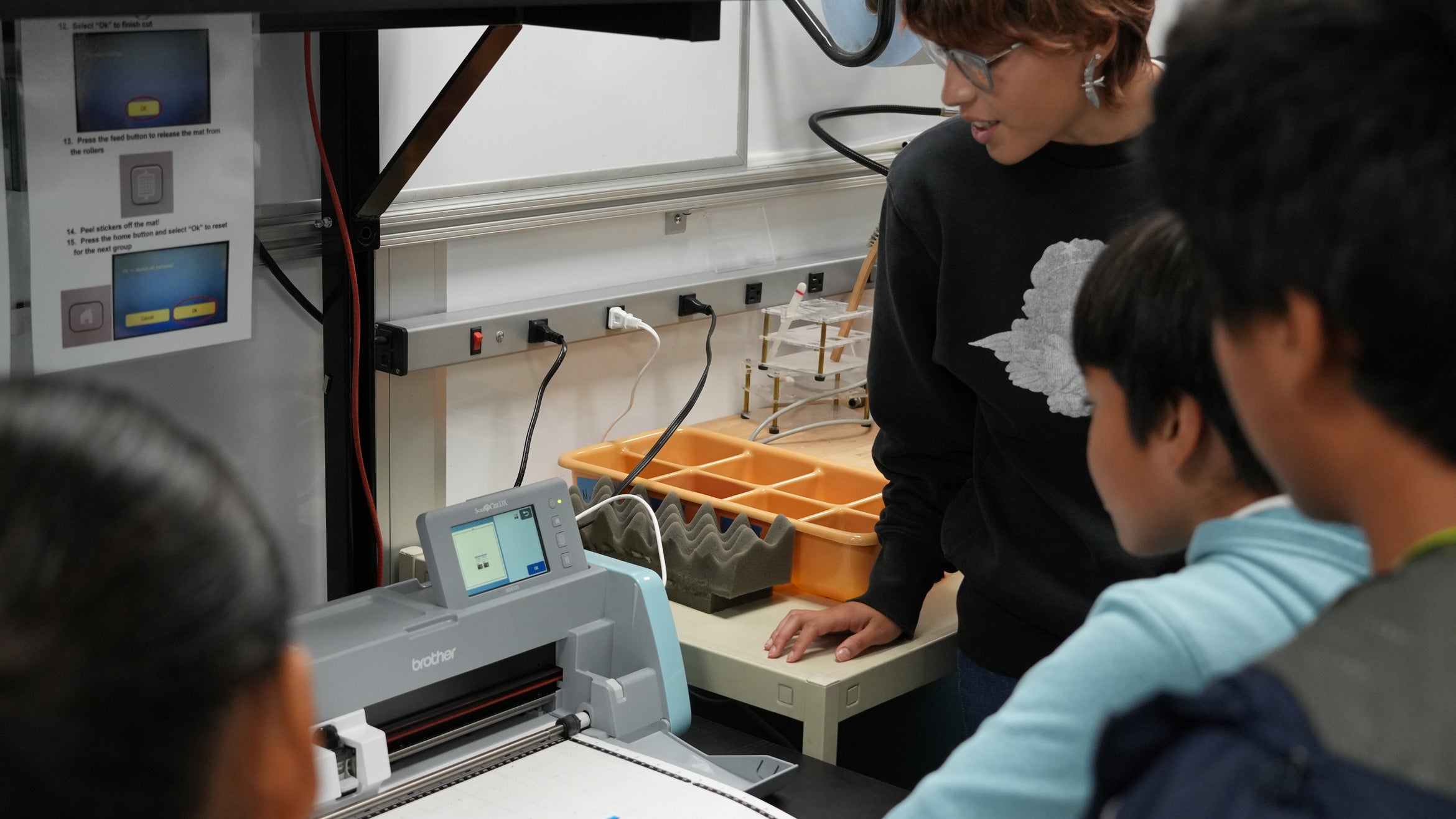 kids look at machine with instructor