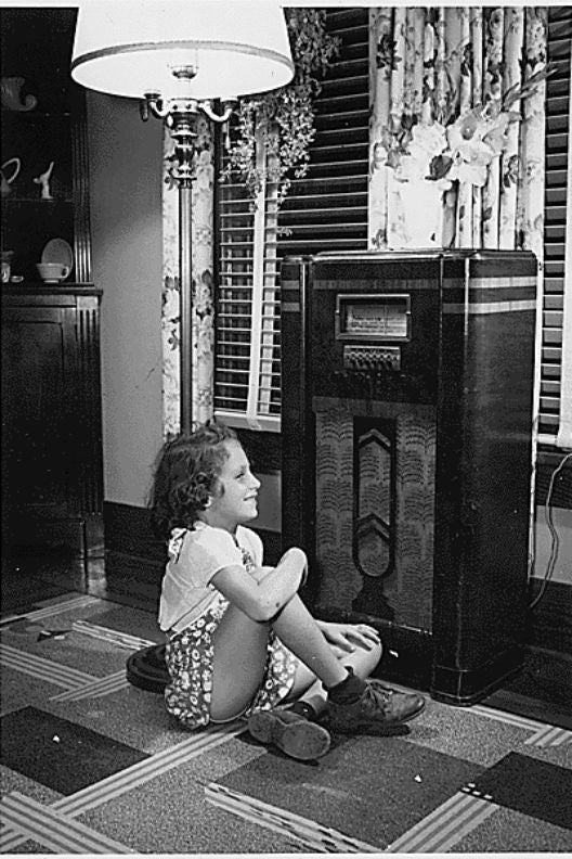 black and white photograph of a young girl listeing to the radio during the great depression