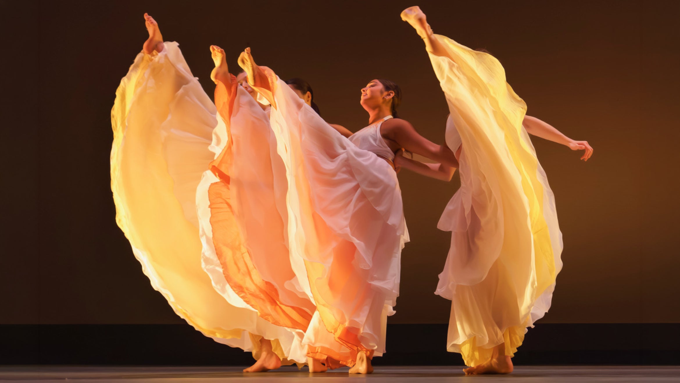 four dancers with flowy yellow skirts