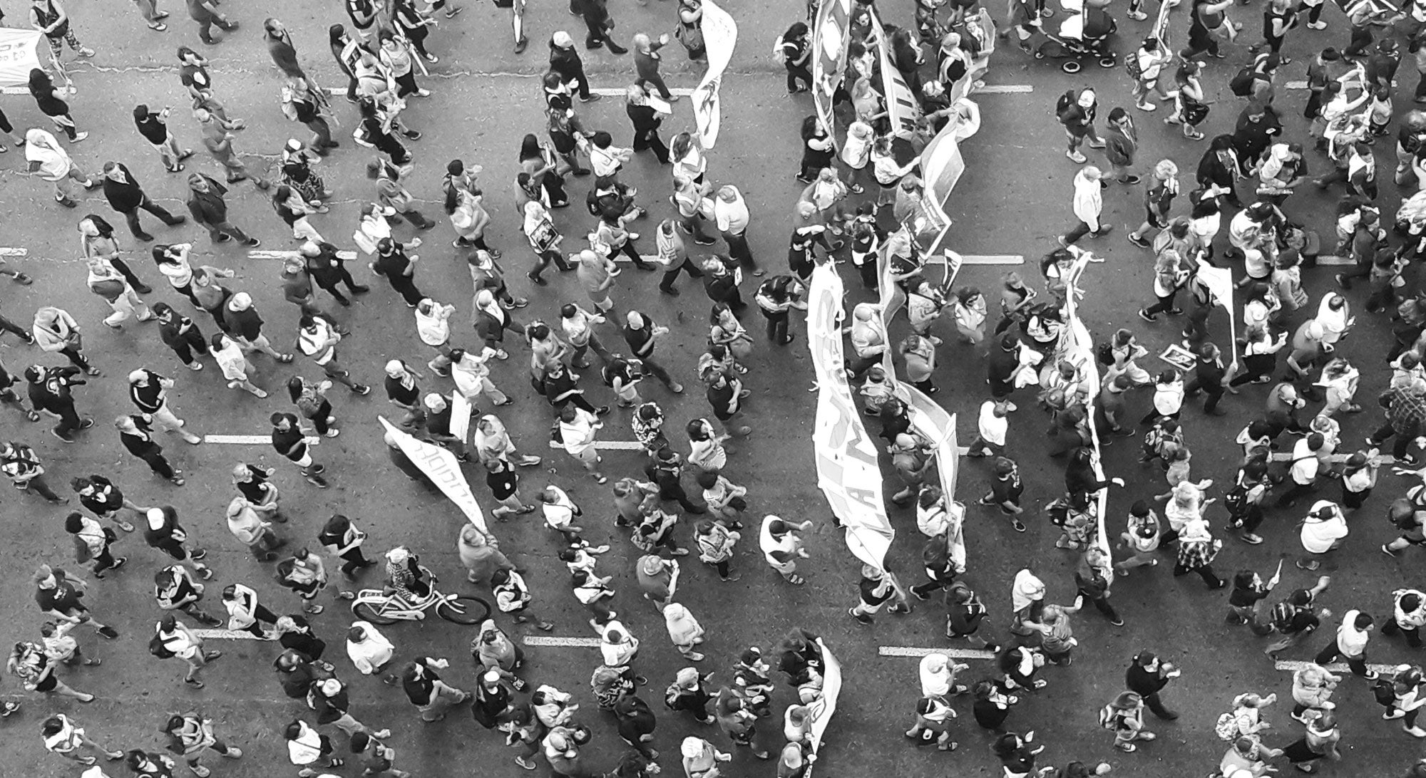 black and white photo with many people marching in one direction taken from up above