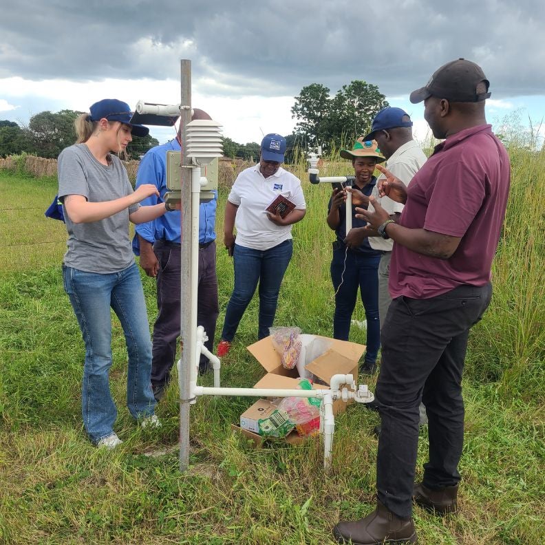 A group of people build a weather station under cloudy skies.