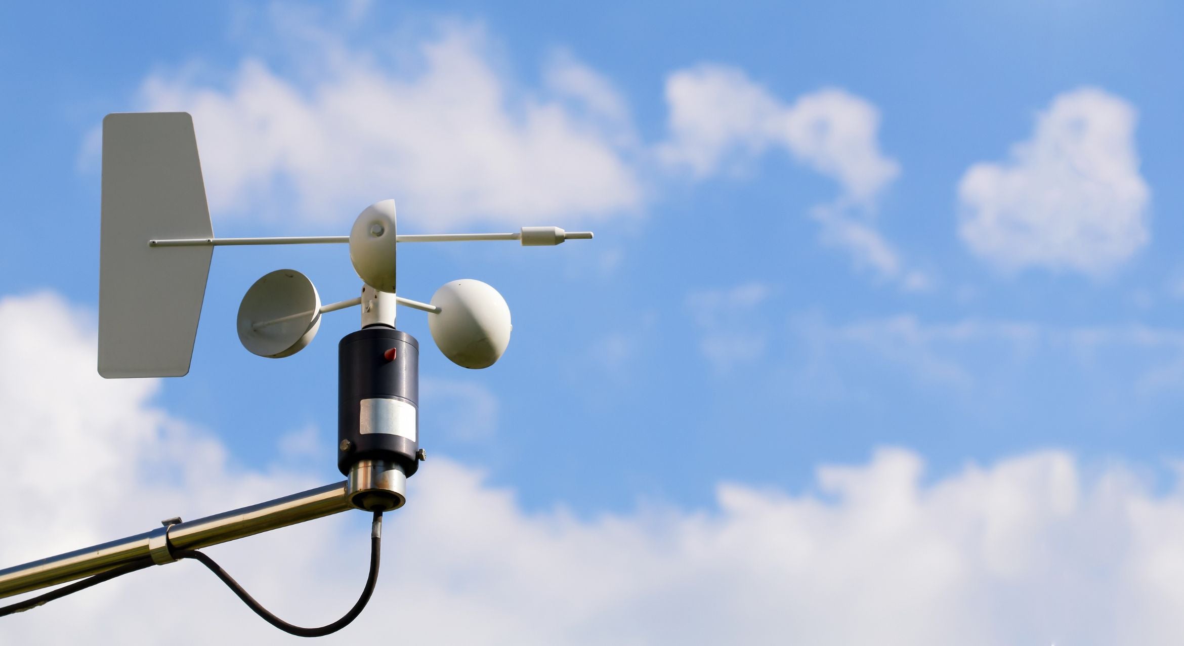 An anemometer against clouds and sky.