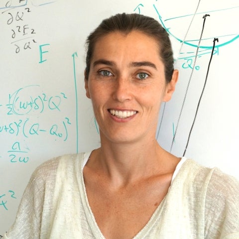 Ania Jayich standing in front of a whiteboard smiling wearing a white blouse