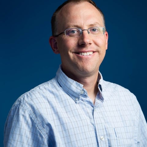 Alex Simms wearing a blue shirt and smiling