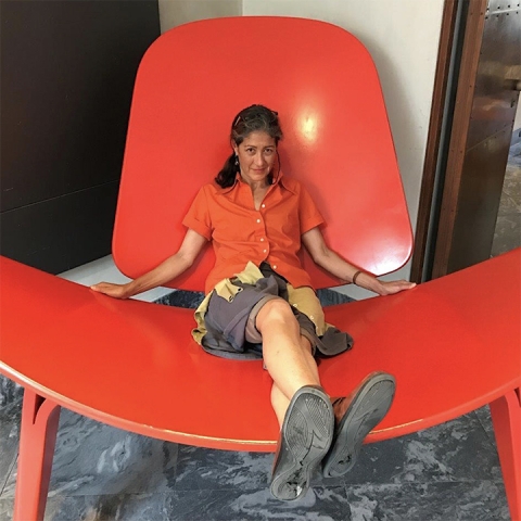 Kim Yasuda sits in a comically oversized red chair