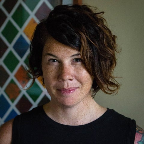 Amy Boddy wears a sleeveless black top with multicolored tiles behind