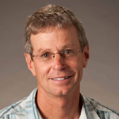 Michael Mahan wears a grey patterned shirt and glasses