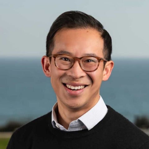 Kyle Meng stands at the shoreline wearing a dark sweater