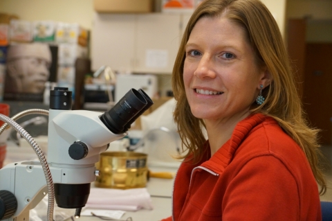Headshot of Amber VanDewarker in her lab near a microscope