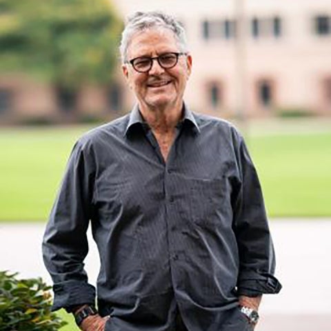 Norbert Reich stands outside in a grey collared shirt