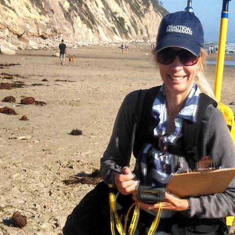 Jenny Dugan stands at the beach with a clipboard