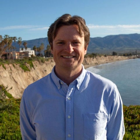 Chris Richardson wears a blue shirt and stands overlooking the ocean
