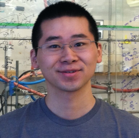 Yang Yang wears glasses and a purple shirt, standing in a lab