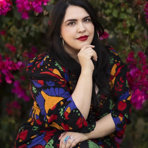 Silvia Rodriguez Vega sits outside wearing a multi-colored dress