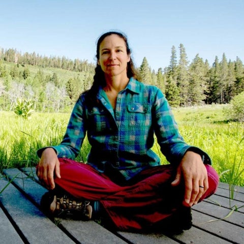 Carol Blanchette sits on a deck amongst a forest