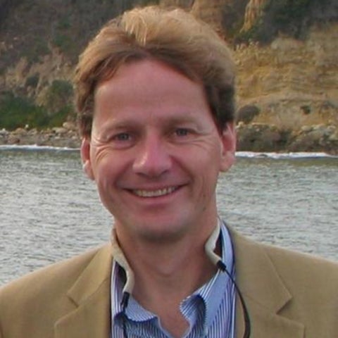 Eckart Meiburg wears a blue shirt under a tan sportcoat near the banks of a river