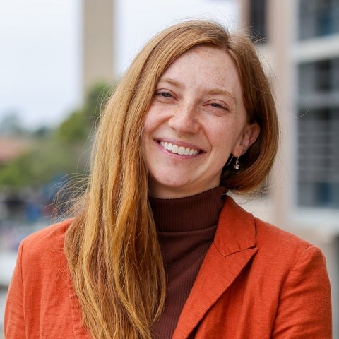 Marley Dewey wears a red blazer over a sweater outside