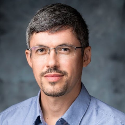 Mike Ludkovski wears a blue collared shirt and glasses