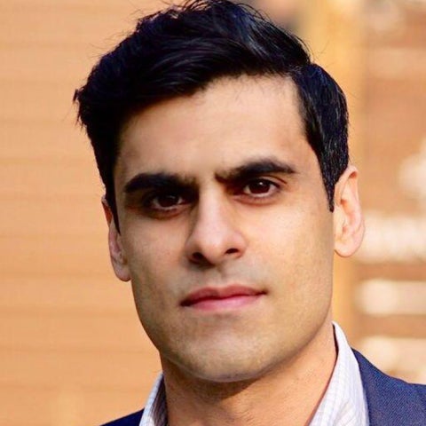 Neil Narang stands outside in a blue blazer and checkered shirt