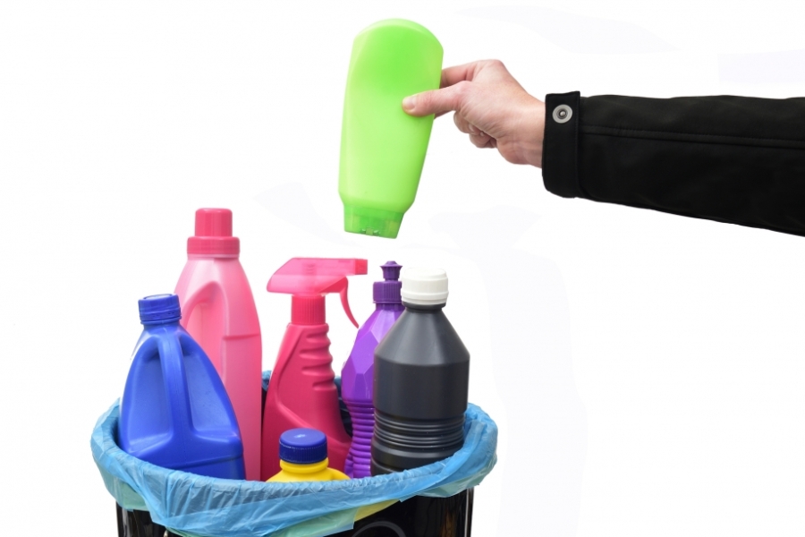 Hand grabbing bottle made of #2 and #4 plastic from trash bin with other plastic bottles